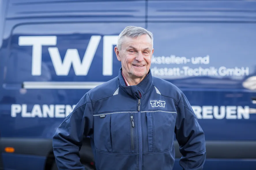 Dieter Friedrich steht vor einem blauen Transporter der TWT